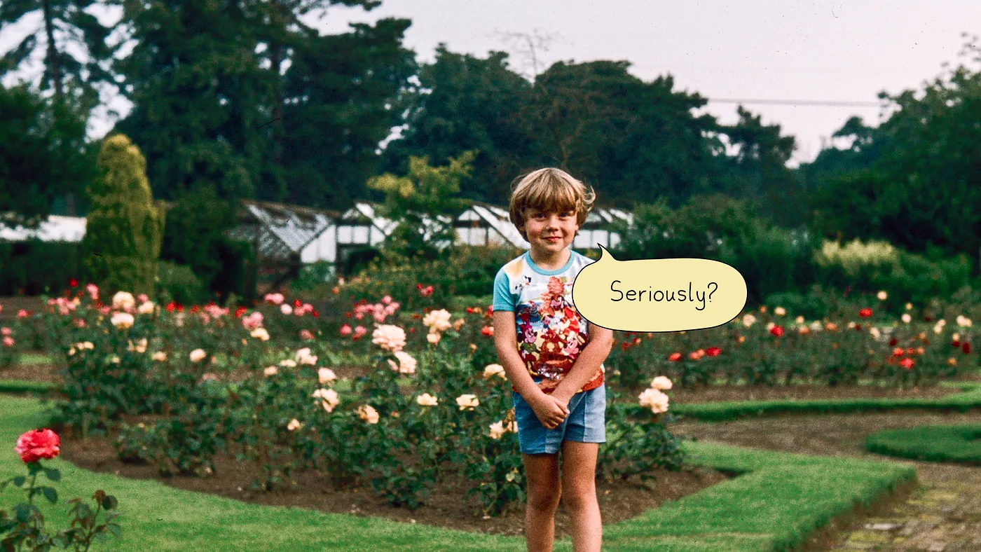 Tom Coates as a child standing in a flower garden and wearing a Winnie the Pooh T-shirt.